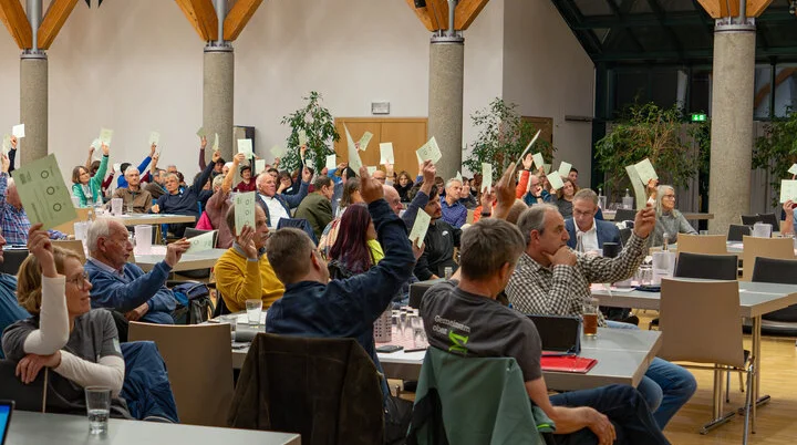 Sitzende Menschen halten Stimmzettel in die Höhe | © DAV Schwaben, Foto: Robin Wilkens